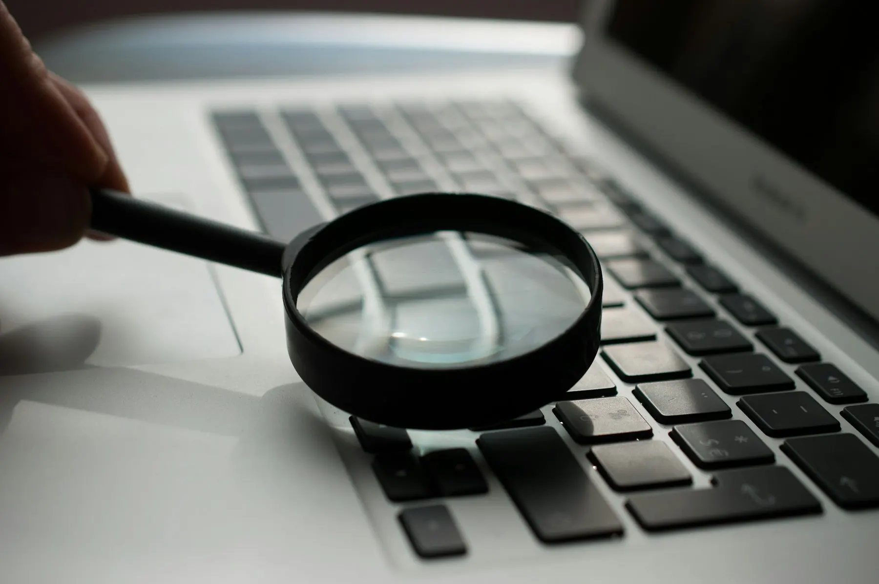 Magnifying glass held over a laptop keyboard