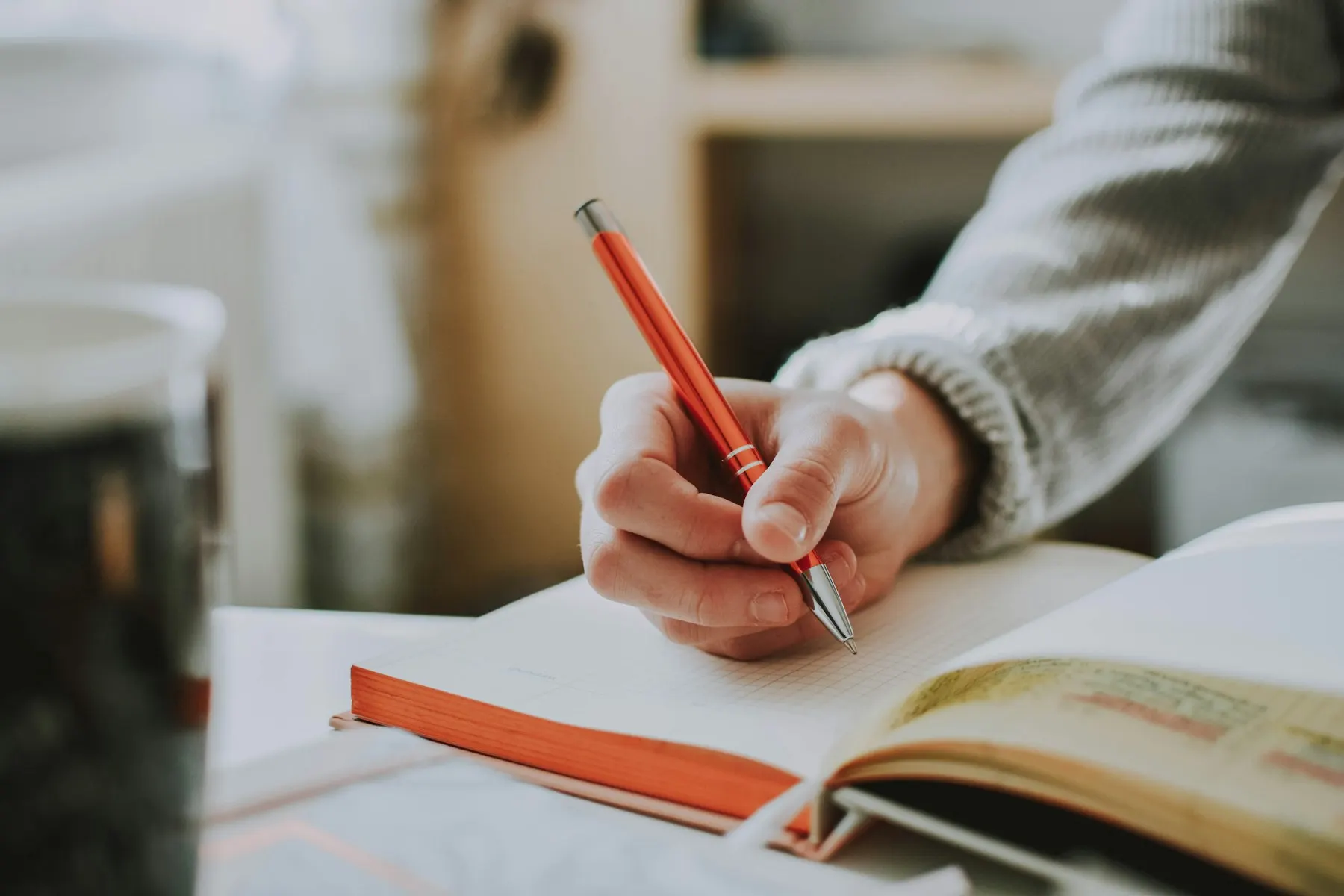 Hand writing in a notebook with a red pen
