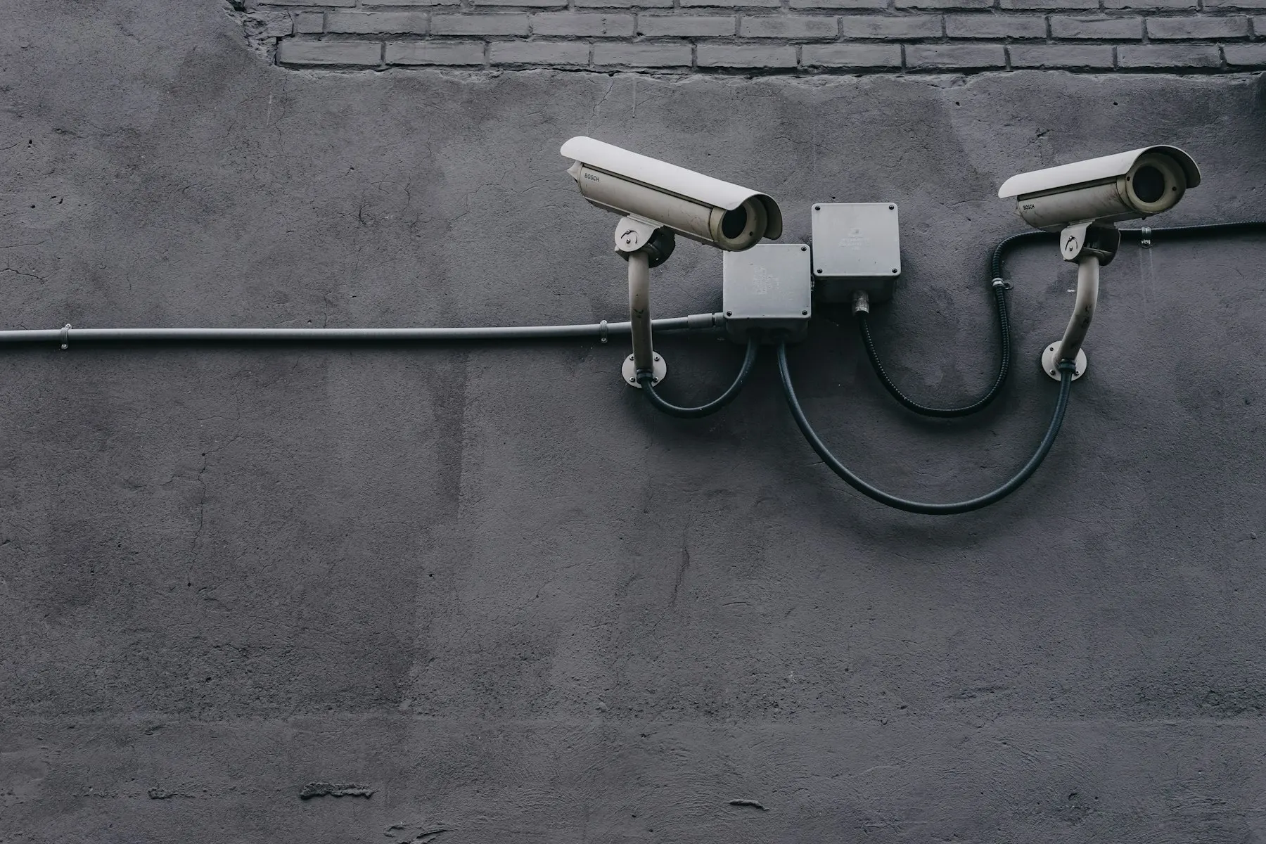 Two security cameras mounted on a grey wall